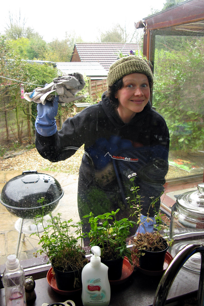 Window cleaner in work clothes wiping a residential conservatory window with a cloth — residential window cleaning service