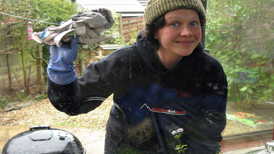 Window cleaner in work clothes wiping a residential conservatory window with a cloth — residential window cleaning service